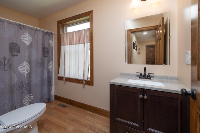 bathroom featuring visible vents, toilet, wood finished floors, baseboards, and vanity