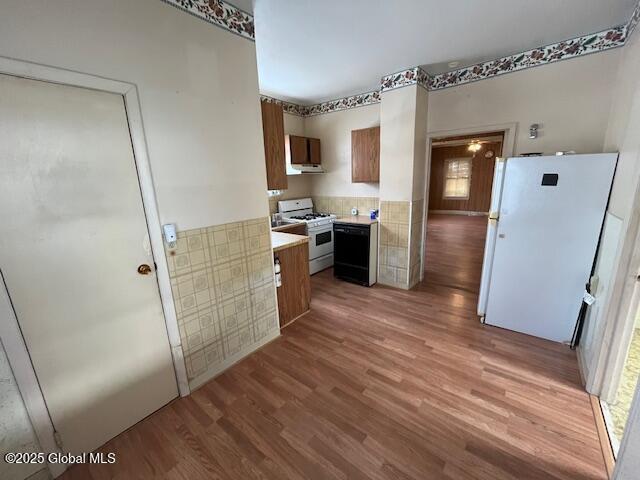 kitchen with white appliances and light hardwood / wood-style flooring