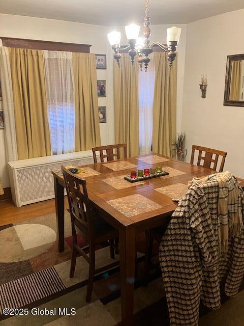 dining room featuring an inviting chandelier, radiator heating unit, and hardwood / wood-style flooring