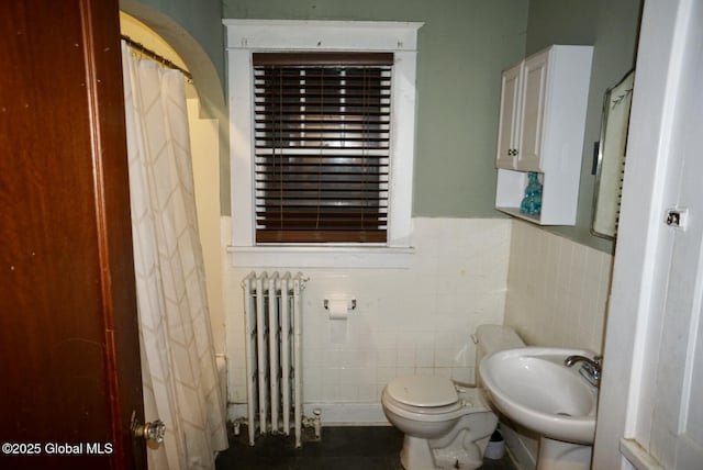 bathroom featuring tile walls, sink, radiator heating unit, and toilet