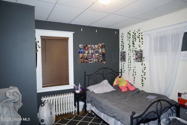 bedroom with a drop ceiling and radiator heating unit