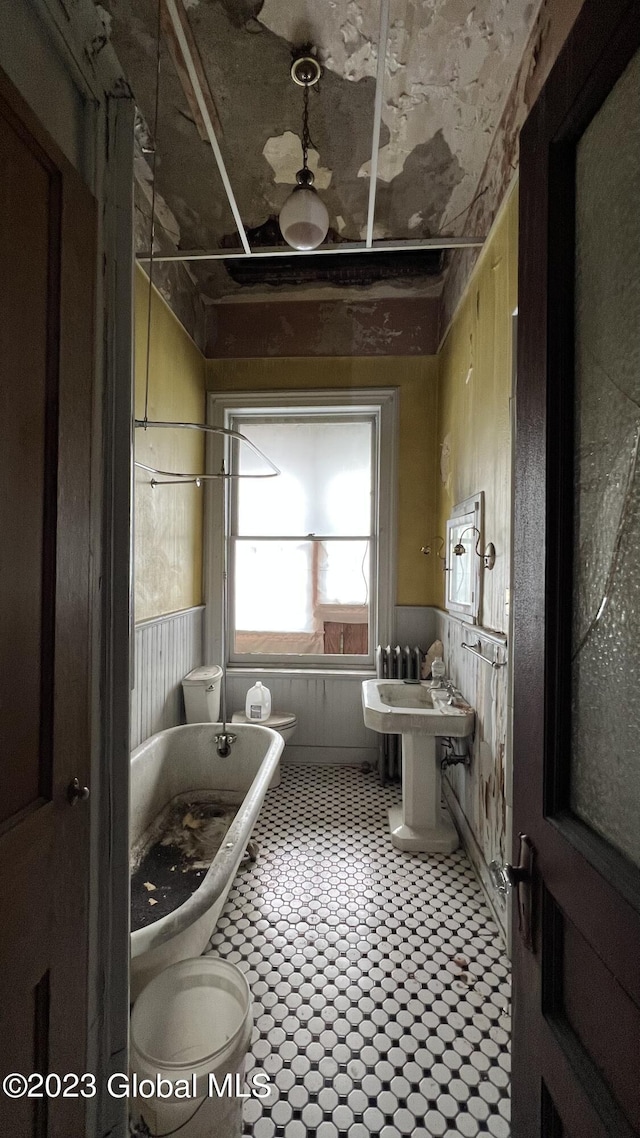 bathroom featuring wooden walls, a tub to relax in, and toilet