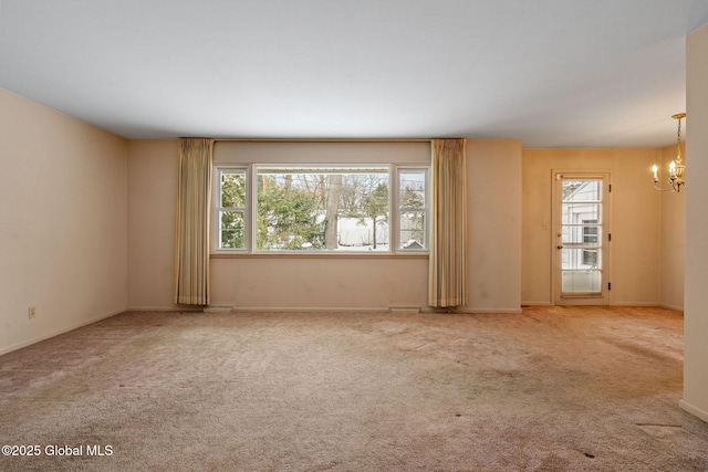 carpeted spare room featuring a chandelier