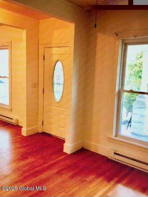 foyer entrance featuring a baseboard heating unit, hardwood / wood-style flooring, and plenty of natural light