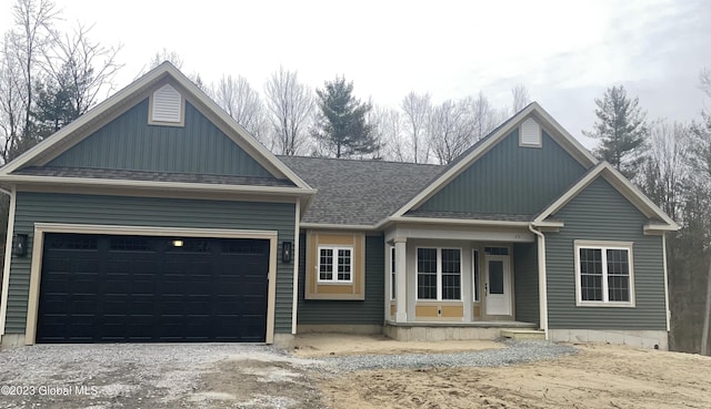 view of front of home featuring a garage, gravel driveway, roof with shingles, and a porch