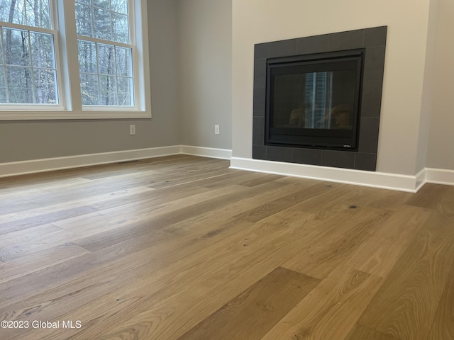unfurnished living room featuring a fireplace, wood finished floors, and baseboards