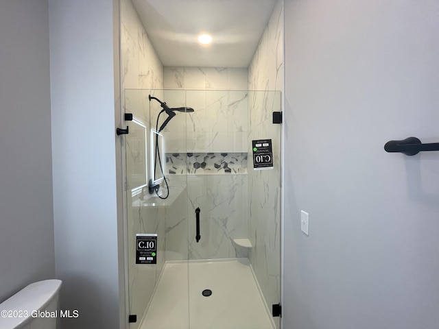 bathroom featuring toilet and a marble finish shower
