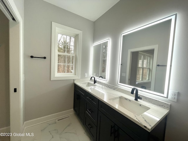 bathroom featuring marble finish floor, double vanity, visible vents, a sink, and baseboards