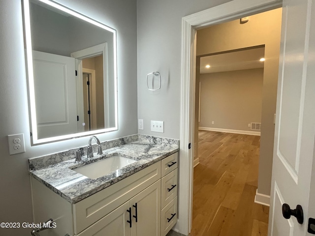 bathroom with vanity, wood finished floors, visible vents, and baseboards