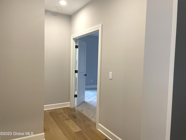 corridor with light wood finished floors and baseboards