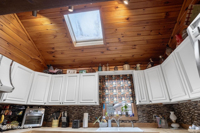 kitchen featuring a sink, tasteful backsplash, and white cabinetry