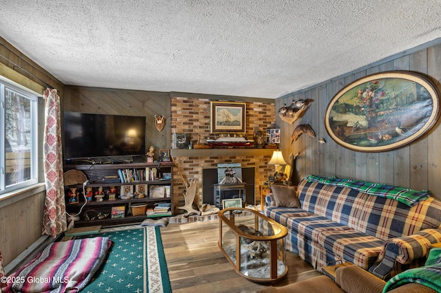 living room featuring a textured ceiling, wood finished floors, wooden walls, and a fireplace