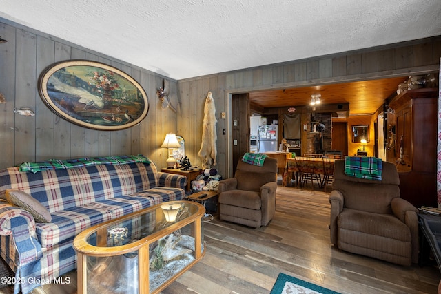 living area featuring wooden walls, wood-type flooring, and a textured ceiling
