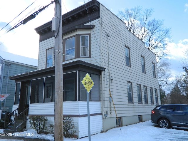 view of snow covered exterior with a sunroom