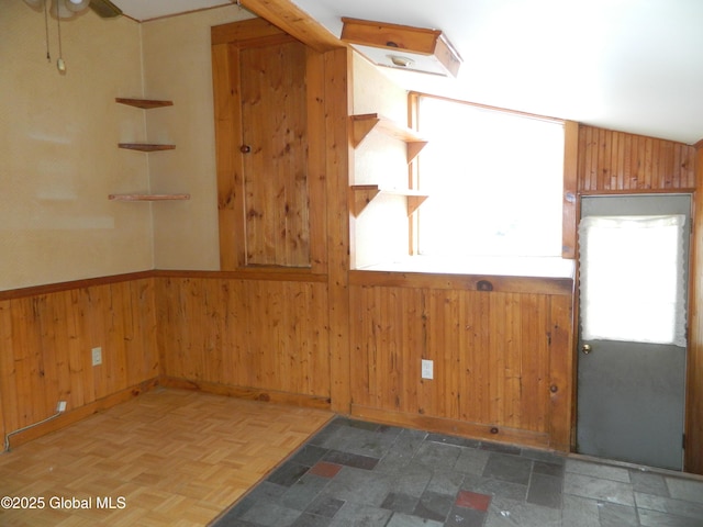 unfurnished room featuring ceiling fan, wooden walls, and dark parquet floors