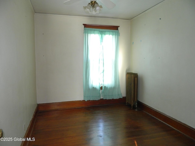 spare room with dark hardwood / wood-style flooring, radiator, and ceiling fan