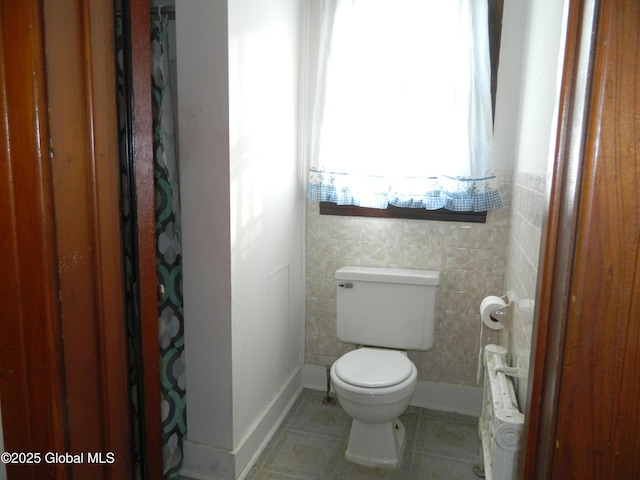 bathroom with tile walls, tile patterned floors, and toilet