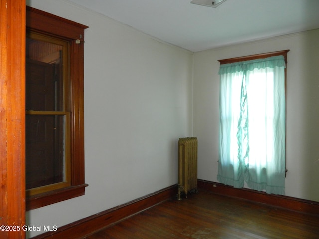 spare room with radiator heating unit and dark hardwood / wood-style floors