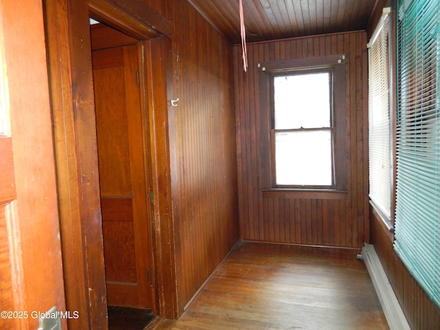 interior space featuring wooden walls, light hardwood / wood-style floors, wooden ceiling, and a baseboard radiator