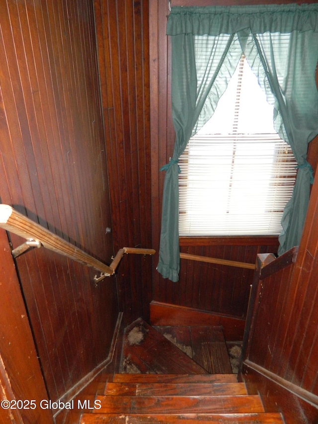 stairway featuring wooden walls