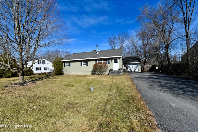 view of front of house featuring a front yard, roof with shingles, a garage, an outbuilding, and driveway