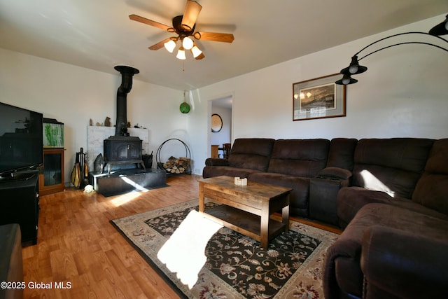 living room featuring ceiling fan, wood finished floors, and a wood stove