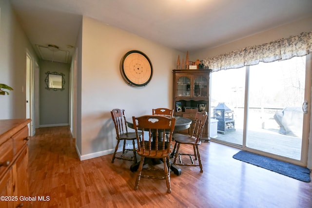 dining area with baseboards, attic access, and wood finished floors