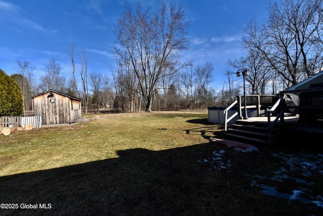 view of yard featuring an outbuilding, a wooden deck, and a storage unit