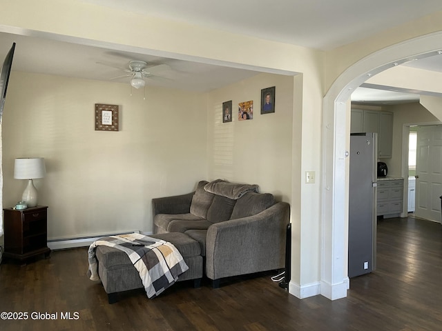 living room featuring a baseboard heating unit, arched walkways, dark wood finished floors, and baseboards