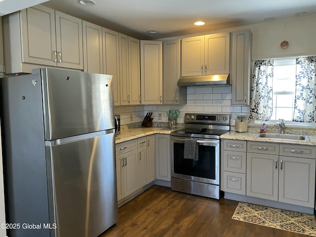 kitchen with dark wood finished floors, appliances with stainless steel finishes, gray cabinetry, under cabinet range hood, and a sink