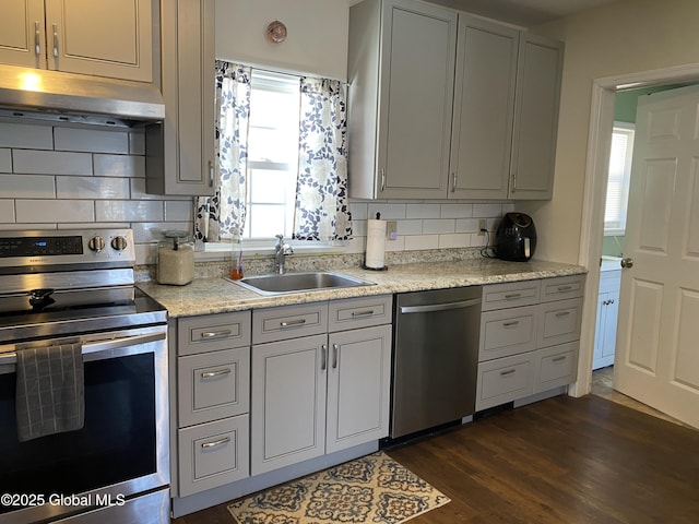 kitchen featuring under cabinet range hood, stainless steel appliances, a sink, and gray cabinetry