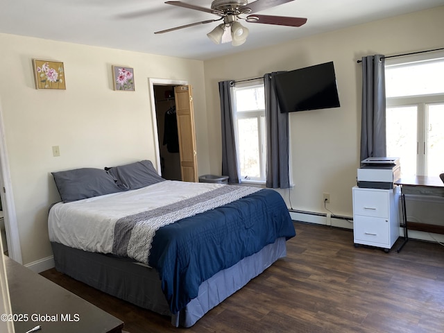 bedroom featuring a baseboard heating unit, dark wood finished floors, and a ceiling fan