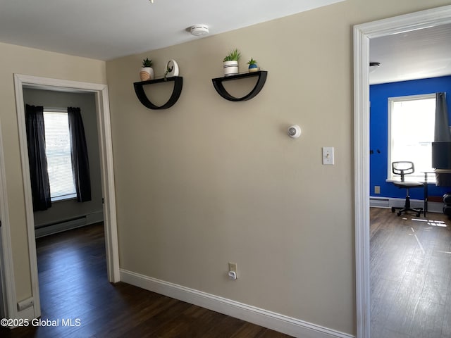 corridor featuring a baseboard radiator, dark wood-style flooring, and baseboards