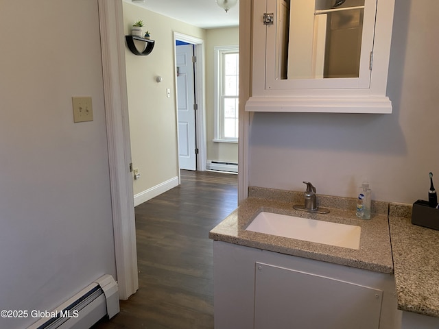 kitchen with dark wood-style floors, baseboard heating, a baseboard heating unit, a sink, and light stone countertops