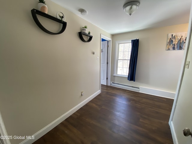 spare room with a baseboard radiator, baseboards, and dark wood finished floors