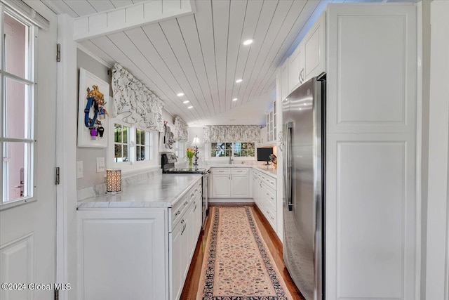 kitchen with wood ceiling, white cabinetry, stainless steel appliances, wood-type flooring, and vaulted ceiling