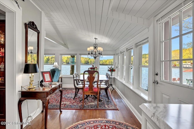 sunroom with an inviting chandelier, vaulted ceiling, wooden ceiling, and a water view