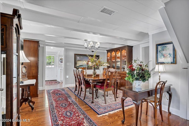 dining space with beamed ceiling, hardwood / wood-style flooring, and a chandelier