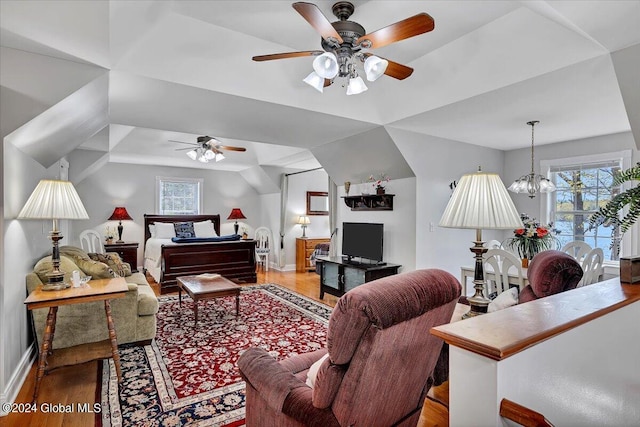 living room with ceiling fan with notable chandelier, lofted ceiling, and hardwood / wood-style floors