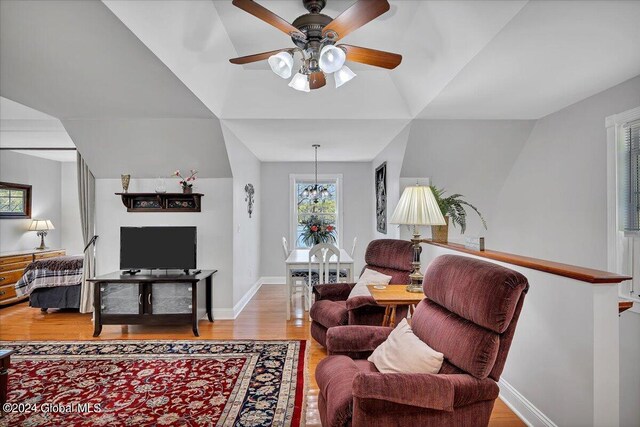 living room with ceiling fan with notable chandelier and light hardwood / wood-style flooring