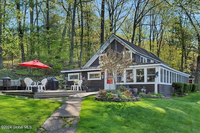 view of front of property featuring a front lawn, a sunroom, and a deck