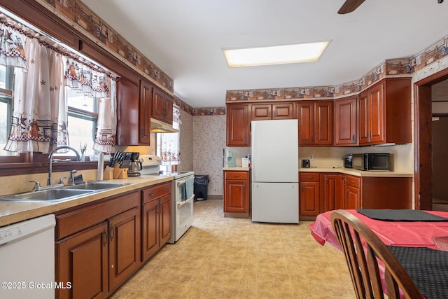 kitchen featuring under cabinet range hood, white appliances, a sink, light countertops, and wallpapered walls