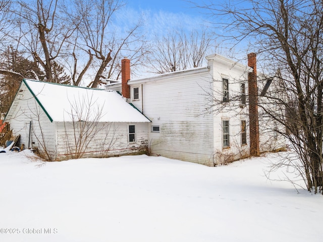 view of snowy exterior with a chimney