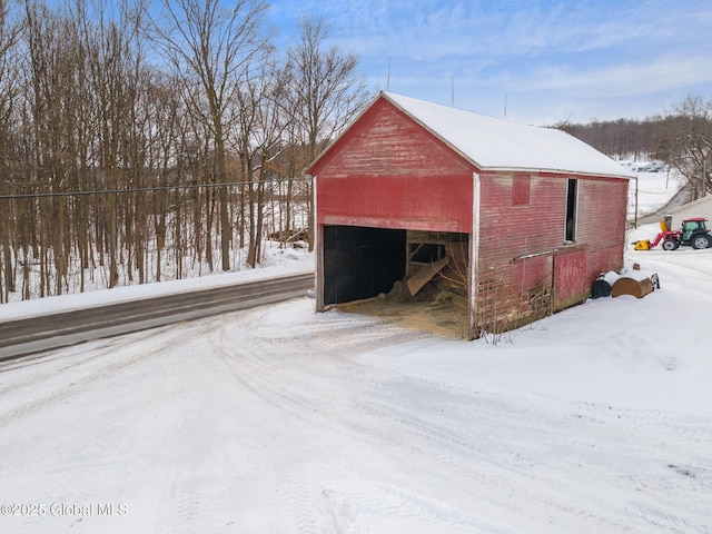 snow covered structure featuring an outbuilding