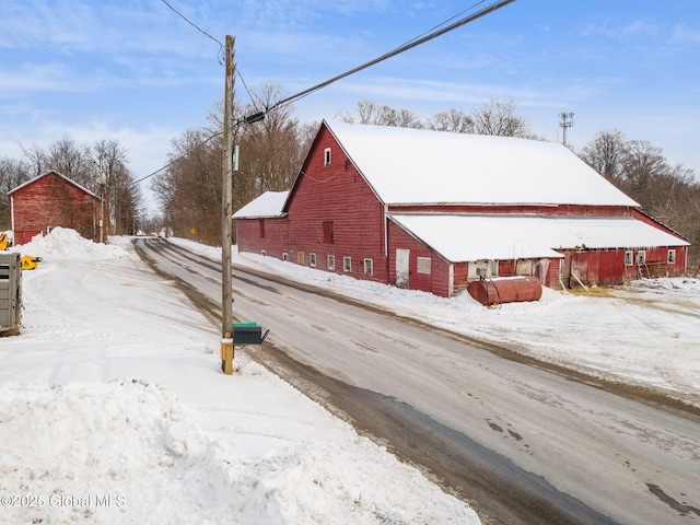 snow covered property with an outdoor structure and a barn