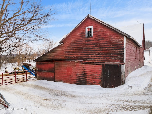 snow covered property featuring a barn, fence, and an outdoor structure