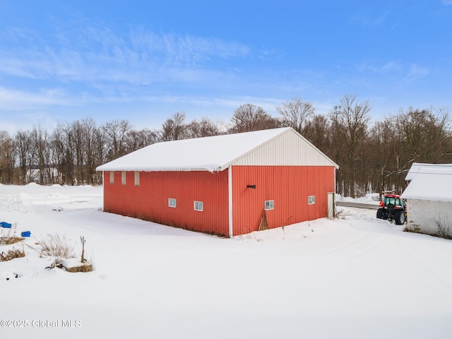 snow covered structure with a pole building and an outbuilding