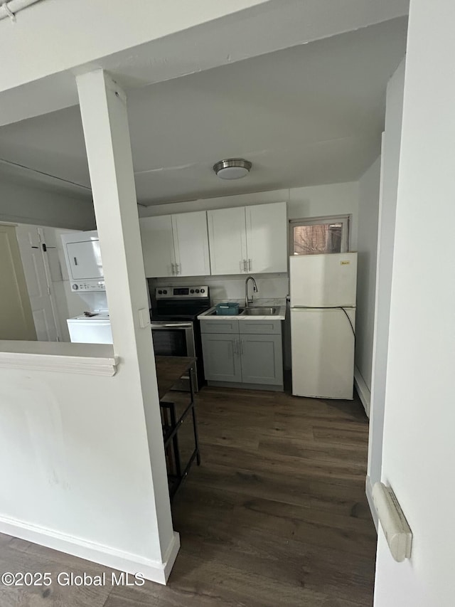 kitchen featuring dark wood-style floors, stainless steel electric range oven, a sink, and freestanding refrigerator