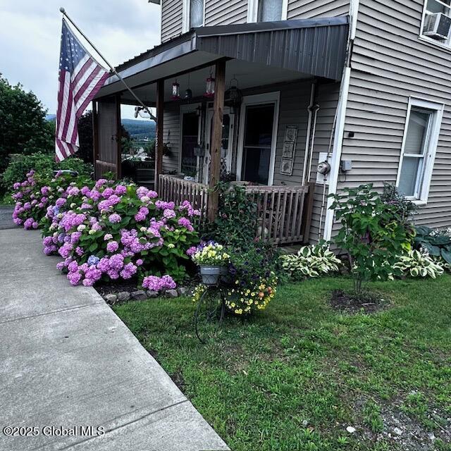 doorway to property featuring a lawn and a porch