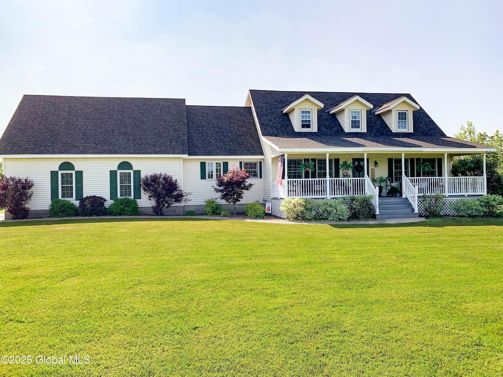 new england style home featuring roof with shingles, a porch, and a front yard